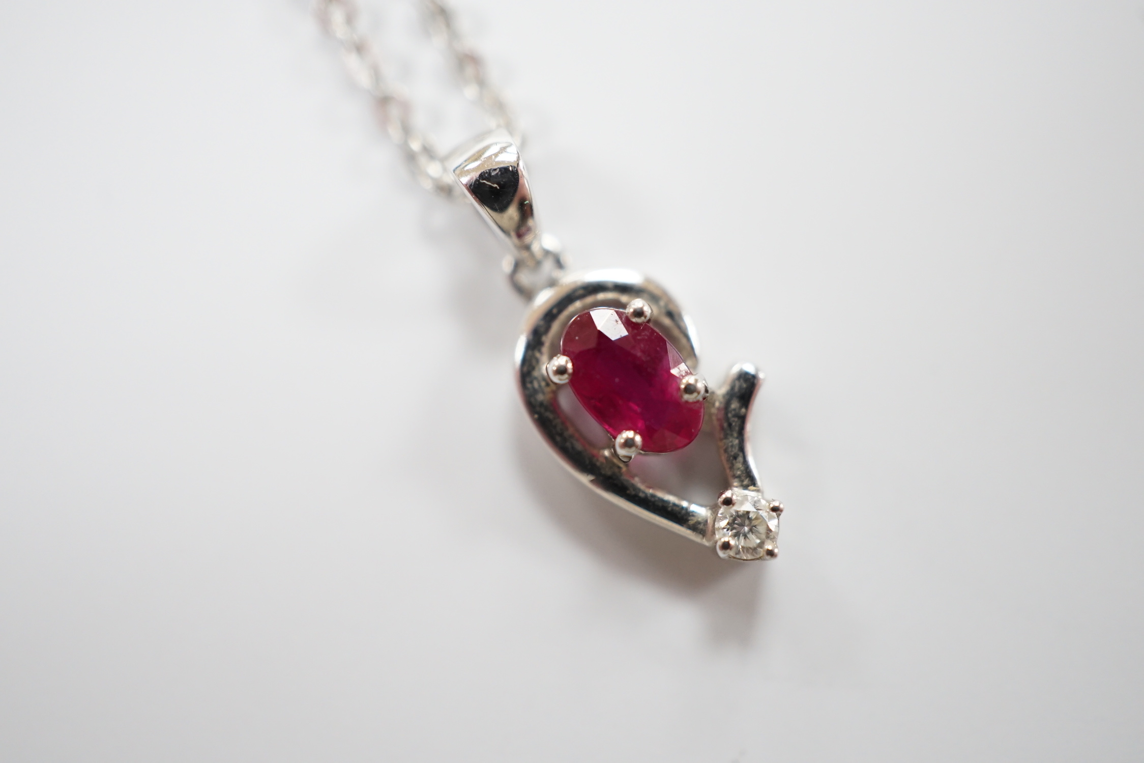 A modern 750 white metal, ruby and diamond set pendant, 9mm, on a 750 white metal chain, 42mm, gross weight 2.6 grams.